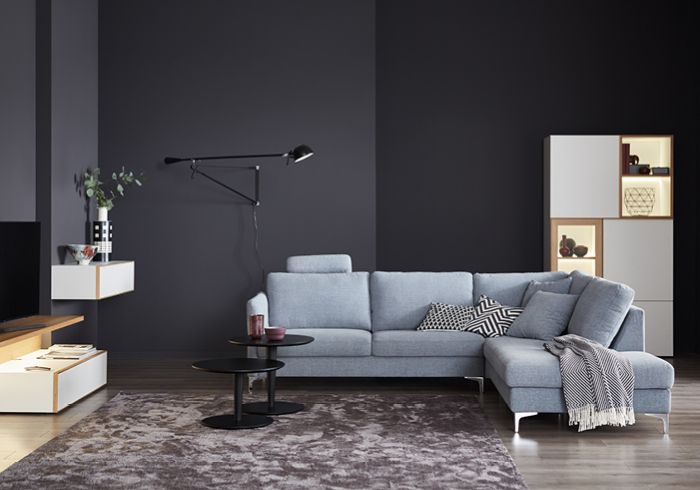 Ein Wohnzimmerausschnitt mit einem grauen L-Sofa und Dekoration