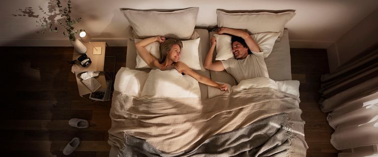 Glückliches Paar, das entspannt in einem gemütlichen Bett liegt