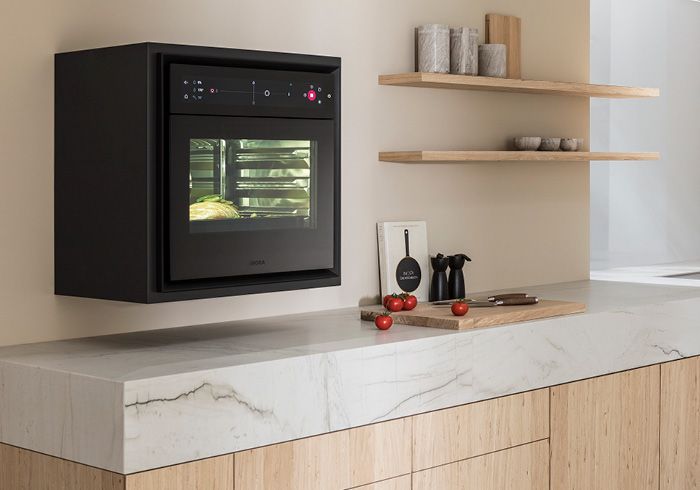 Moderner Wandofen in schwarzem Design neben offenen Holzregalen in einer stilvollen Küche.